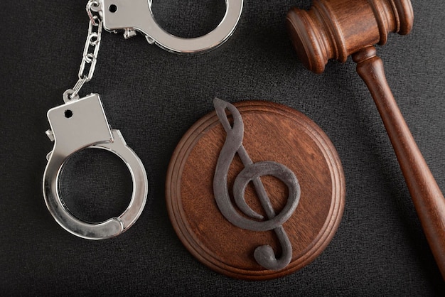 Photo treble clef sign and handcuffs. illegal use of someone elses music. punishment for intellectual property infringement. music licensing.