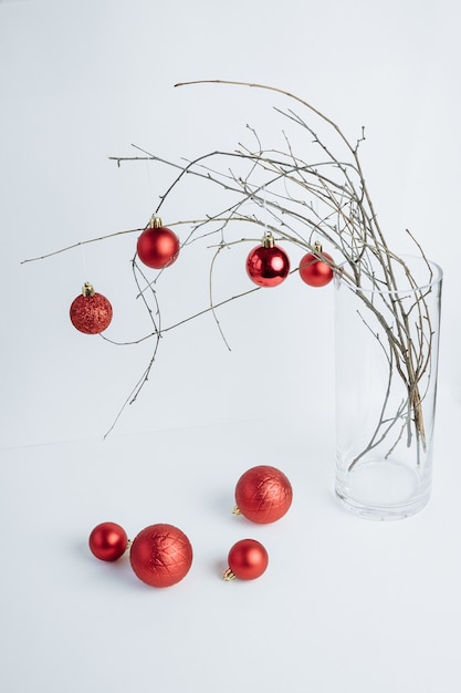 빨간색 장식품으로 장식 된 꽃병에 나무 branhes 크리스마스 컴포지션 흰색 배경 세로