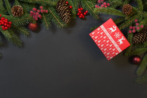 Albero, regali, bacche di agrifoglio e decorazione sul nero.