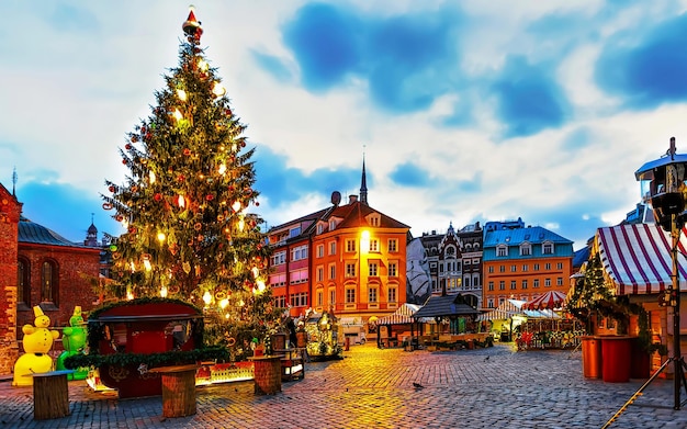 겨울 리가, 라트비아의 돔 광장에 있는 밤 크리스마스 시장의 나무. 시장에서 공예품이 있는 Advent Fair 장식 및 포장 마차. 라트비아어 거리 크리스마스와 휴일