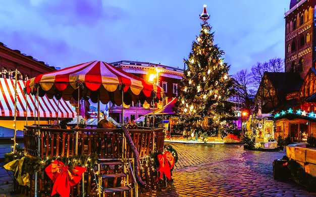 Albero di notte mercatino di natale sulla piazza del duomo in inverno riga, lettonia. decorazione della fiera dell'avvento e bancarelle con oggetti di artigianato sul bazaar. messa a fuoco selettiva