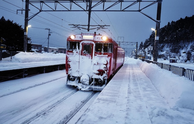 Trein op een met sneeuw bedekte spoorlijn tegen de lucht tijdens de winter