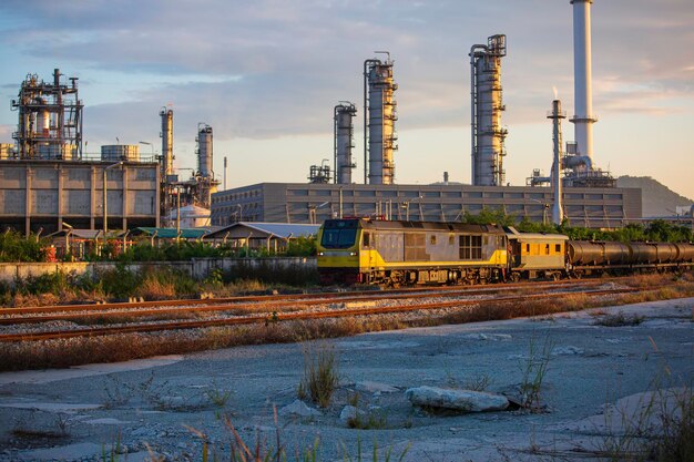 Foto treinspoorweg verder voor zeehaventorenkolom van container uit de petrochemie-industrie op treinspoorweg;