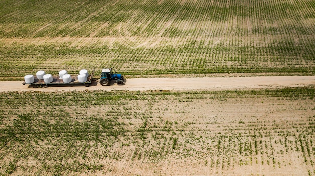 Trekker rijdt op het veld en draagt balen hooi luchtfoto