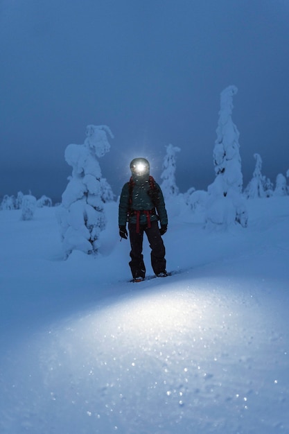 Trekker with a headlamp walking in a snowy Riisitunturi National Park, Finland