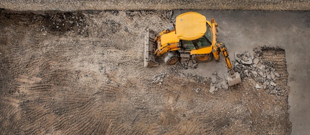 Trekkergraafmachine reinigt het bovenaanzicht van het reparatiewerk van de asfaltlaag