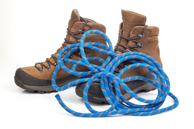 trekking boots for hiking next to a climbing rope on a white background Travel and Hiking Equipment