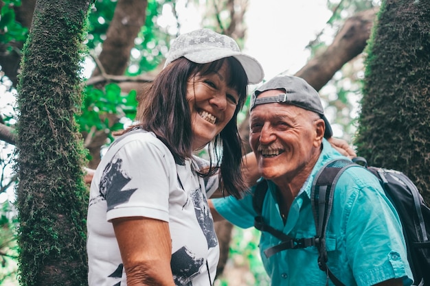 Photo trekking day in the forest for a happy senior couple looking at camera smiling enjoying nature