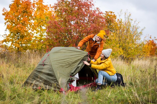 trekking and hiking concept happy young couple sets up green tent in autumn forest