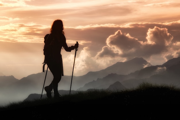 Trekking in solitude among the mountains. Silhouette of a girl