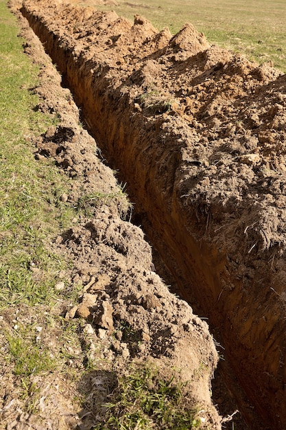 A trench for laying cable Lines of trenches dug in the field Vertical snapshot