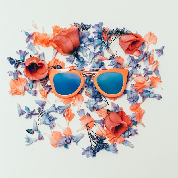 Foto occhiali da sole di tendenza su sfondo di fiori. l'estate sta arrivando.