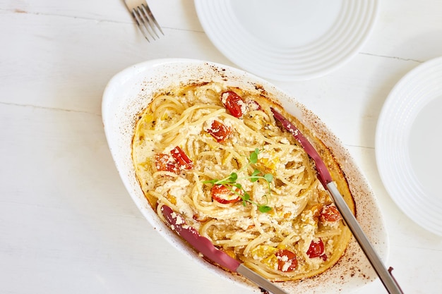 Trending virale recept van gebakken tomaten en feta met pasta, Fetapasta op een witte houten achtergrond