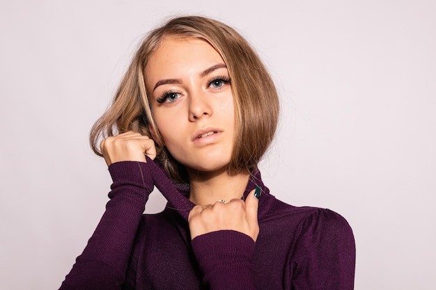 Trendy beautiful hipster girl. Photo of positive young nice woman in burgundy knee-high socks with white background. looks at the camera. pulls golfers