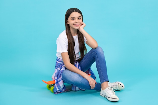 Trendy beautiful teenage model posing on blue studio background Child girl in tshirt and jeans Studio shot Teen fashion Teenager lifestyle