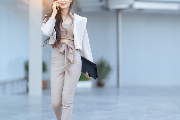 Trendy beautiful young Asian woman carrying colorful bags shopping online with mobile phone with copy space