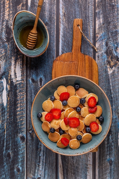 Colazione alla moda con mini pancake, mirtilli e fragole, vista dall'alto.