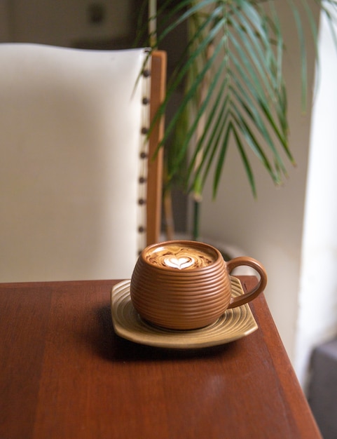 Trendy brown cup of hot cappuccino on wooden table background