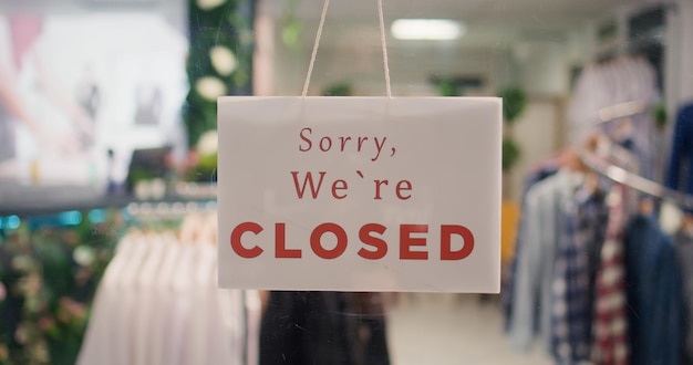 Photo trendy clothing store being closed at night after finished working hours extreme close up shot on sorry we are closed message sign on fashion boutique door in mall at shift end