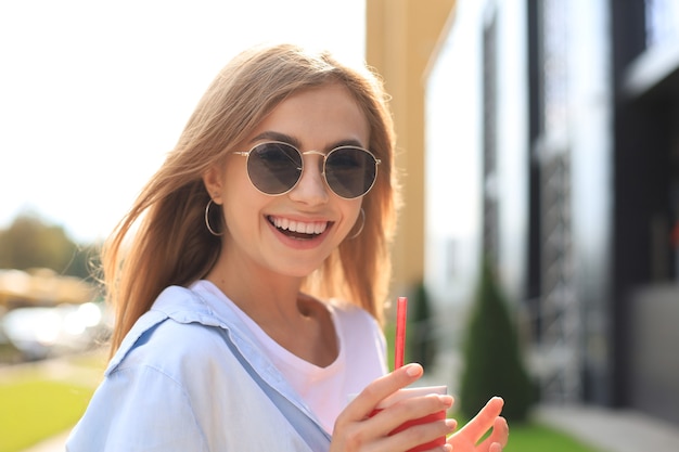 Trendy cool hipster girl drink cocktail in urban city background.