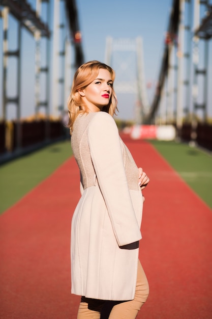 Trendy dressed stylish model posing at the street in light of sun