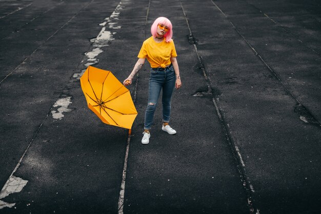 Adolescente etnico alla moda che tiene ombrello giallo brillante