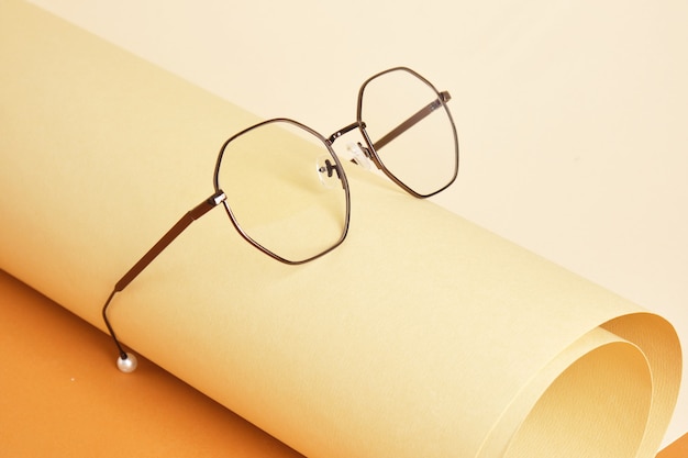 Trendy eyeglasses on rolled beige paper