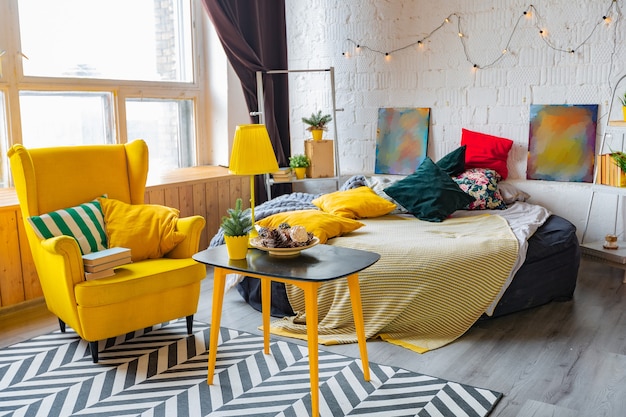 Trendy fashion luxury interior design in Scandinavian style of studio apartment with bright yellow furniture and decorated with lights