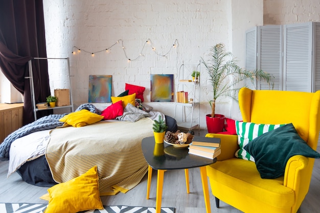 Trendy fashion luxury interior design in Scandinavian style of studio apartment with bright yellow furniture and decorated with lights