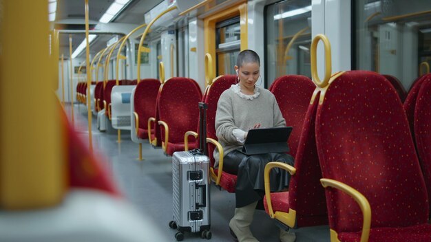 Trendy freelancer working train looking on laptop screen informal woman typing