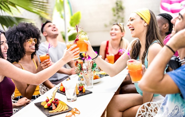 Trendy friends drinking cocktails at poolside party