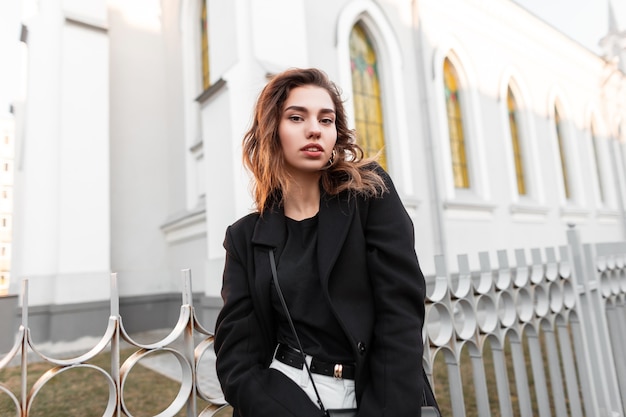 Trendy girl in black fashion clothes walks outdoors