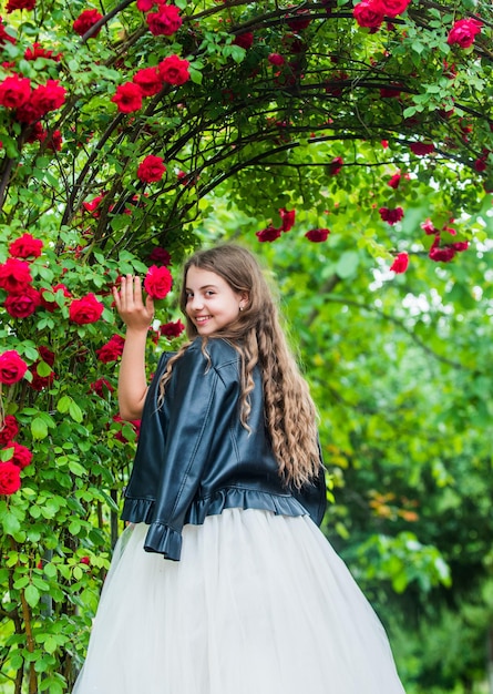 Trendy girl fancy dress and leather jacket in roses garden stylish princess concept