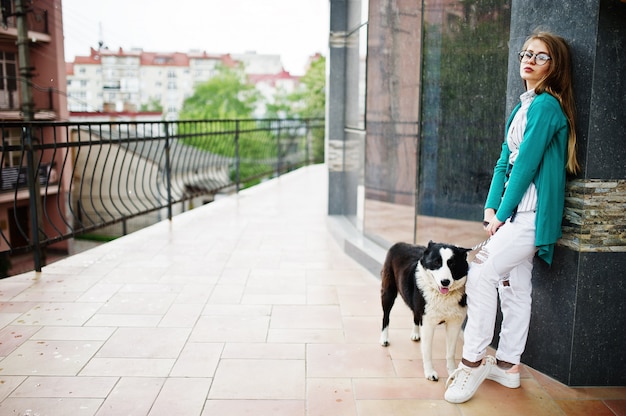 안경의 유행 소녀와 도시의 거리에 대하여 가죽 끈에 러시아 유럽 라이카 (허스키) 강아지와 찢어진 청바지