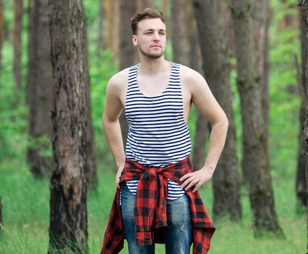 Trendy guy is resting in a pine forest