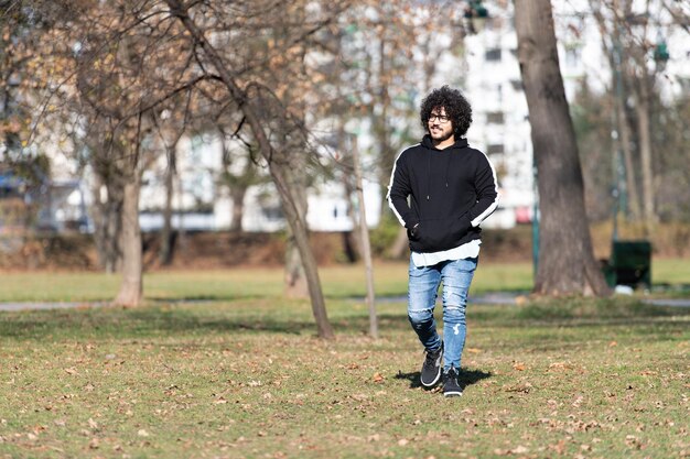 Uomo bello alla moda che posa nel parco d'autunno da solo