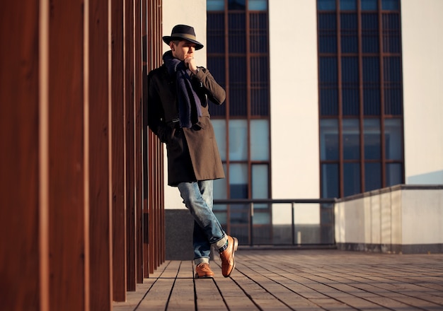 Trendy handsome young man in autumn fashion standing in urban environment.