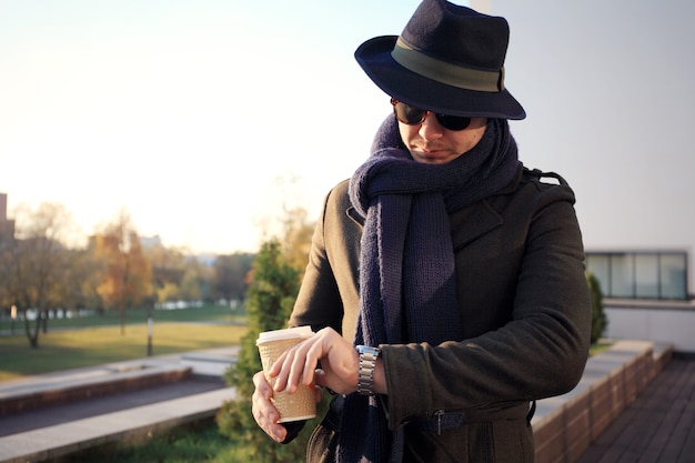 Trendy handsome young man in autumn fashion standing in urban environment.