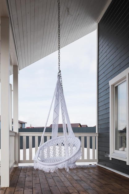 Trendy hanging chair on the veranda of a country house