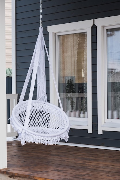 Trendy hanging chair on the veranda of a country house