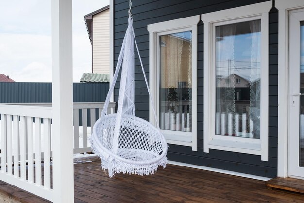 Trendy hanging chair on the veranda of a country house.