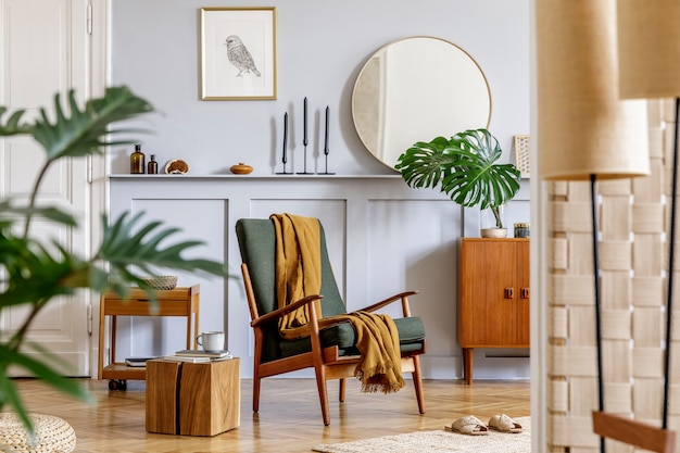 Photo trendy interior of living room with design armchair, vintage commode, round mirror, mock up poster frame, shelf, tropical leaf, decoration, carpet and persnoal accessories in home decor.