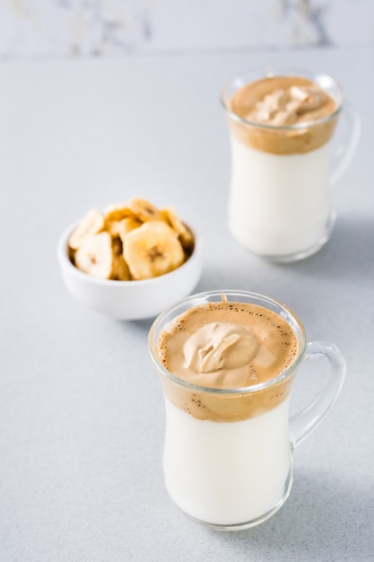 Trendy keuken in quarantaine plaatsen. twee kopjes met dalgonakoffie en bananenchips in een kom op grijs