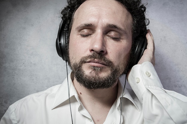 Photo trendy, listening and enjoying music with headphones, man in white shirt with funny expressions