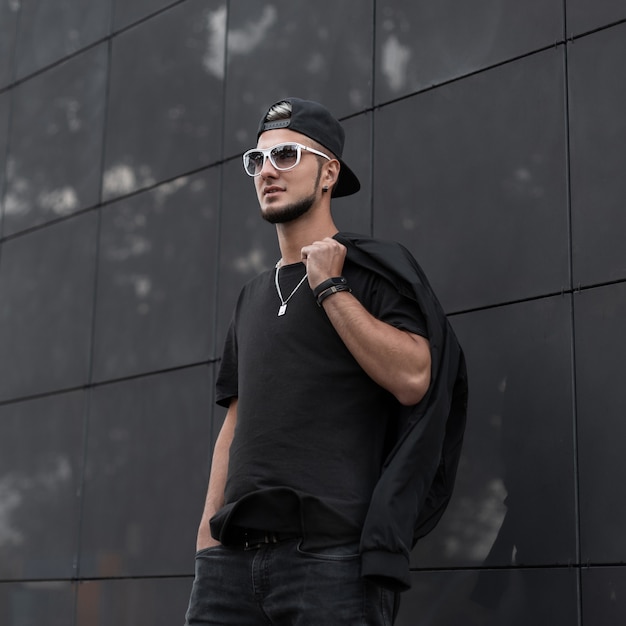 Trendy man in black clothes walks on the street 