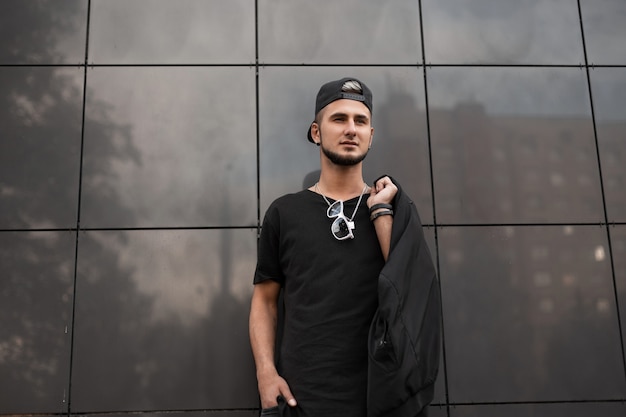 Trendy man in black clothes walks on the street 