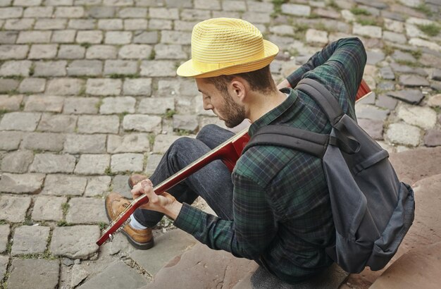 Trendy man die gitaar speelt op straat