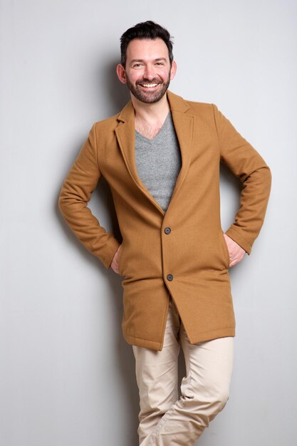 Trendy man with coat posing against gray background