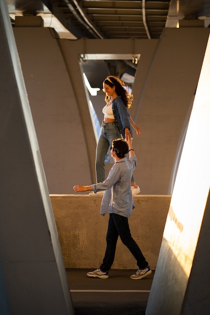 Trendy man and woman walk under bridge casual couple in street style clothes and trendy sunglasses