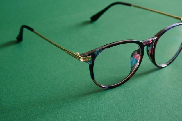 Trendy modern eye glasses on green background copy space